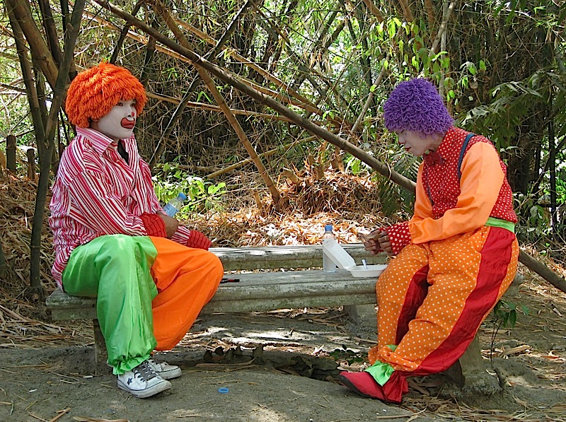 two clowns eating lunch under a bamboo grove