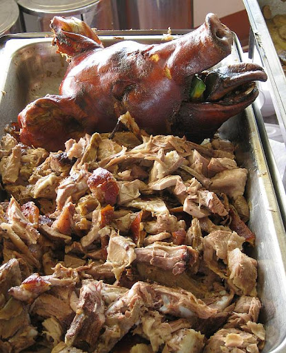 lechon pieces on a platter with the head of the roast pig