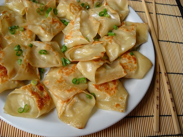 finished pot stickers on white plate with chop sticks 