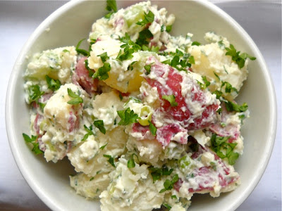 Potato salad in a white bowl, overhead view, garnished with parsley.