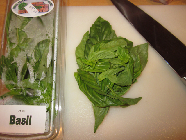 Package of fresh basil with a few leaves taken out to chop with knife 