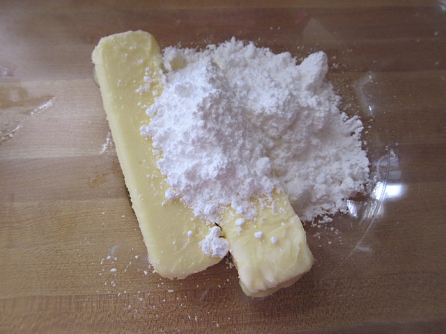 butter and powdered sugar in clear mixing bowl 