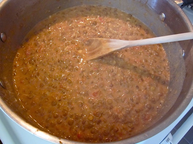 finished lentils in pot with wooden spoon 