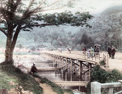 Togetsukyo bridge in Arashiyama, Kyoto, Japan. Horinji Temple can be seen on the hillside. Women in kimono stand on the bridge, a man is fishing under a cherry tree. A boat passes under the bridge. The bridge was destroyed by a flood in 1892. Late 19th century albumen photograph by Tamamura Kozaburo (1856-19??).
