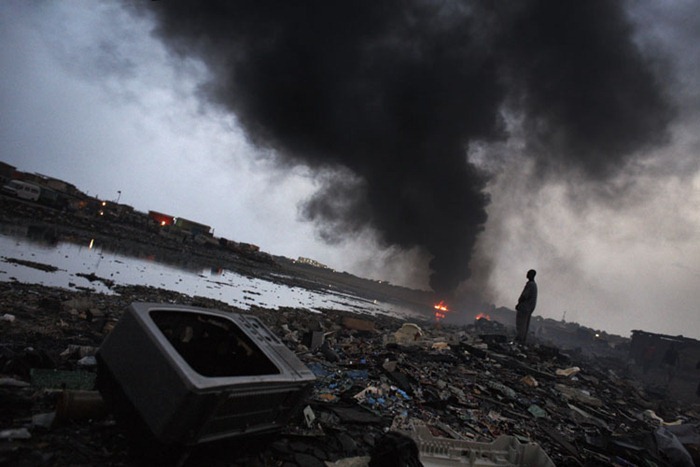 E-waste litters the ground while a huge fire burns at Agbogbloshie dump, in Accra, Ghana.