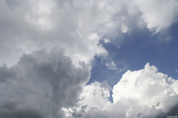 Ciel bleu, nuages blancs et gris.