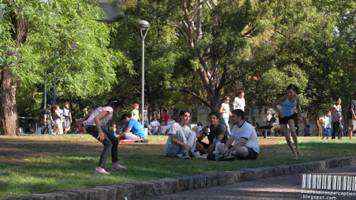 Girls Playing Tag while Boys Drinking Mate in the Parque Centenario in Buenos Aires, Argentina