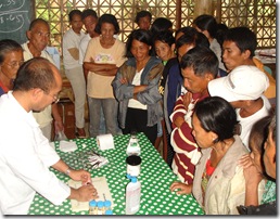 Dr. Edgar Amar (leftmost) demonstrates on the disease diagnosis. Right: Fisherfolk  take turns glancing into a microscope