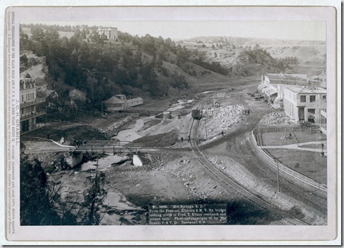 Title: "Hot Springs, S.D." From the Fremont, Elkhorn and M.V. Ry. bridge looking north to Fred T. Evans residence and plunge bath
Bird's-eye view of a developing small town with railroad track running through it. Large buildings on hilltops in background. 1891.
Repository: Library of Congress Prints and Photographs Division Washington, D.C. 20540