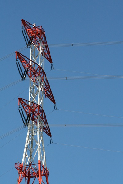 Red and white power tower against a deep blue sky