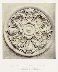 rond plafondornament, een reliëf met afgebeeld de vier winddrichtingen in hoofden.