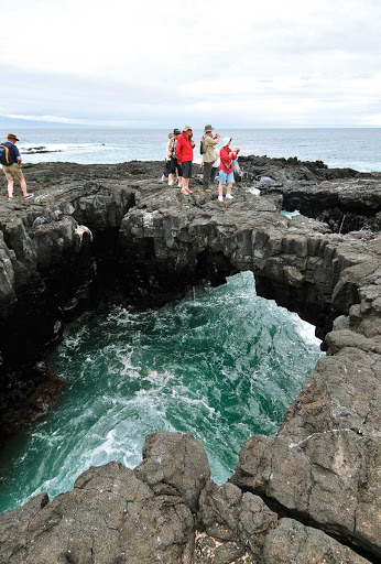 Silversea guests explore a crevice on Santiago Island in the Galapagos.