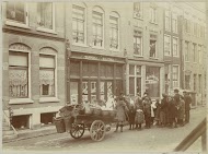 Kinderen en volwassenen kijken toe bij werkzaamheden voor een tapperij annex slijterij en wafelbakkerij Jac. van der Zee