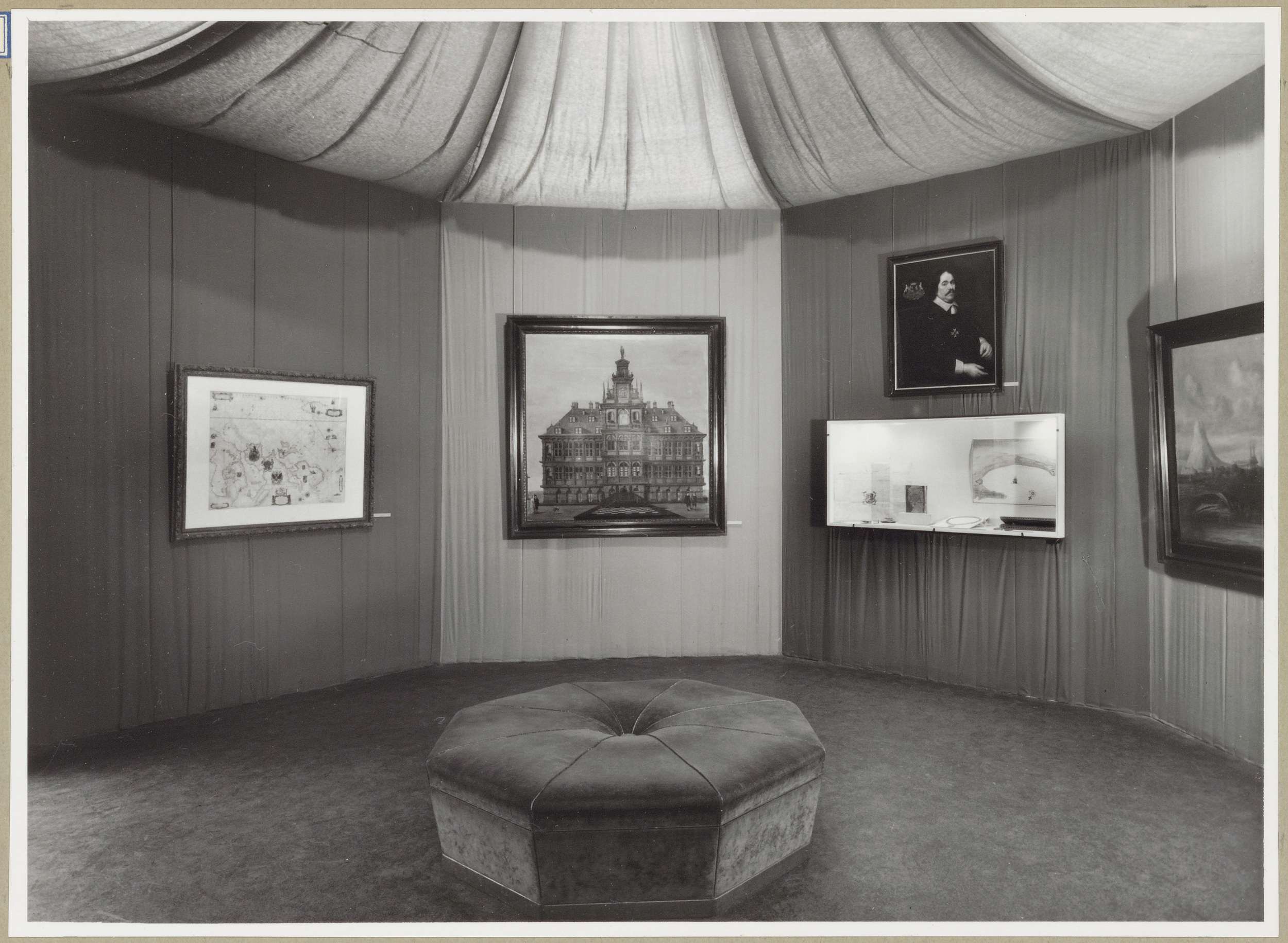 Hoekzaal met rechts een portret boven een vitrine