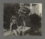 Klaas en Tiny Kleiterp zittend op een muur bij een huis in Singkawang