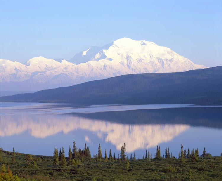 The magnitude of the snow-capped peaks reflect in this lake in Denali National Park, Alaska.