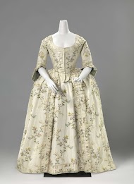 Rok met zijsplitten van witte zijde met meerkleurige gebrocheerde verticale bloemslingers, langs de onderrand een geplooide strook met zijden lint en opengewerkt randje.