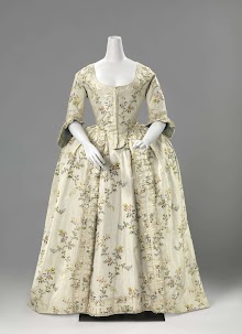 Rok met zijsplitten van witte zijde met meerkleurige gebrocheerde verticale bloemslingers, langs de onderrand een geplooide strook met zijden lint en opengewerkt randje.