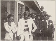 Indonesische mannen en vrouwen, op de achtergrond een Europese man, vermoedelijk op een haventerrein