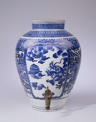 Eivormige pot (fonteinpot) met bloeiende planten bij een rots