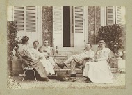 Vrouwen, een man, een baby en een hond poserend in een tuin