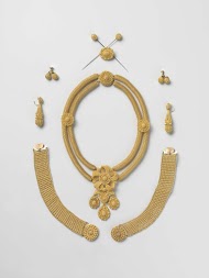 Parure van goud bestaande uit een collier, een paar armbanden, een broche, een paar oorhangers, een stel manchetknopen, twee haarnaalden en een hanger