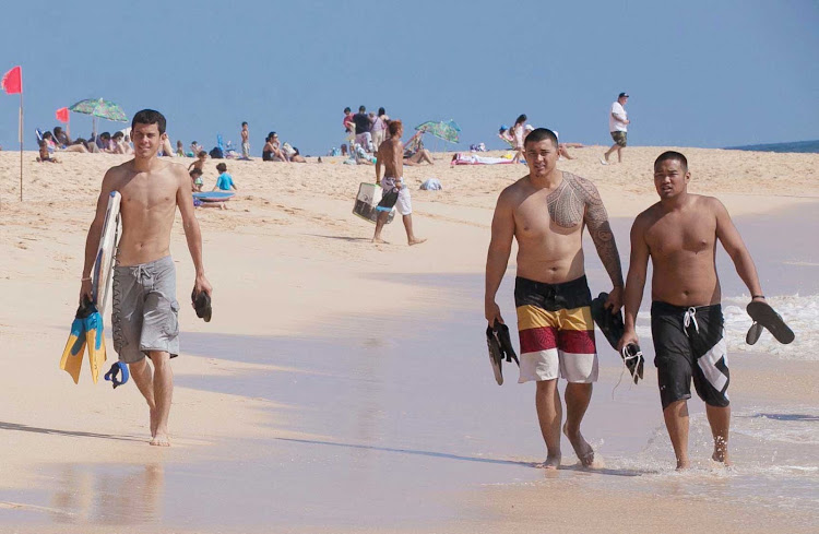 The scene on Sandy Beach in Honolulu, including great-looking tattoos, a 45-minute drive from downtown Waikiki. Sandy Beach draws experienced bodysurfers for its large shore breaks and strong waves.