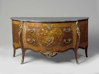 Commode met twee laden en een deur aan de zijkanten. Marqueterieversiering met ruiten, rozetten en vlechtwerk en midden twee duiven, bloemwerk, boog, toorts en pijlenkoker.